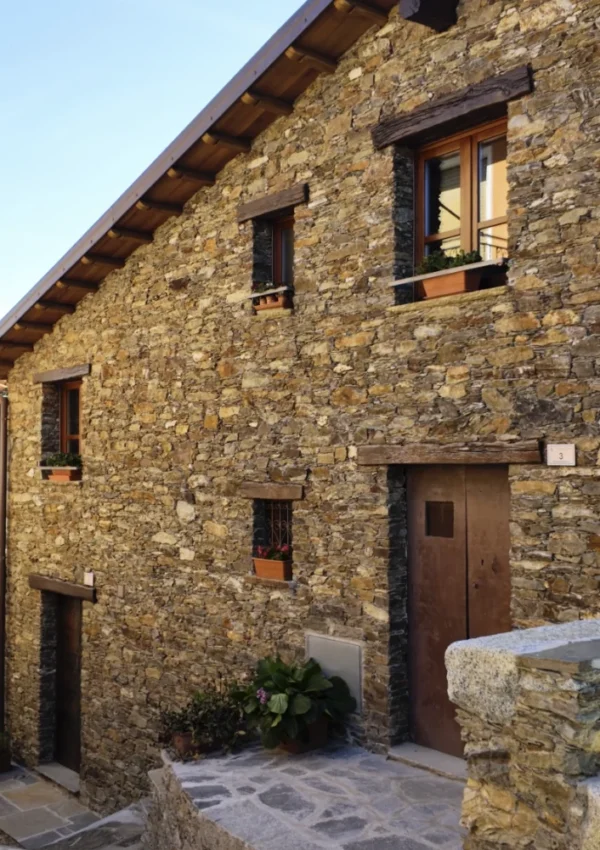 Casa desulese, facciata in pietra con porta in legno Edificio rurale in pietra con finestre ad arco e porta in legno scuro, tipica architettura di Desulo.