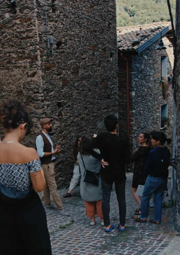 Centro storico di Desulo, Gruppo di persone in un vicolo Piccolo gruppo di giovani riuniti in un vicolo lastricato tra edifici in pietra, in visita guidata.